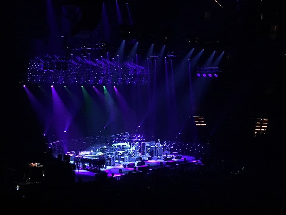 Phish performing under elaborate concert lighting at Xcel Energy Center in Saint Paul, with a sold-out crowd stretching across the arena floor and lower bowl