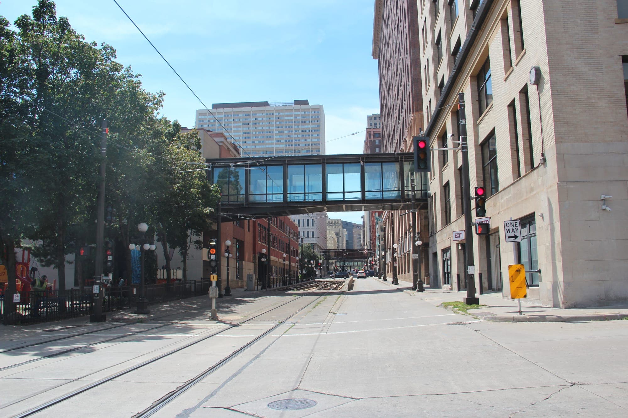 A glass-walled skyway bridge crossing 4th Street in downtown Saint Paul on a sunny day.